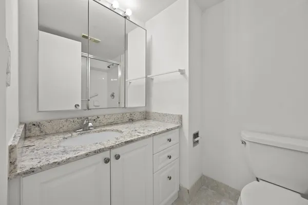 a bathroom with a granite countertop sink a mirror and a toilet