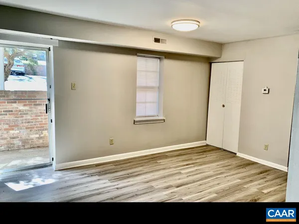 a view of an empty room with wooden floor and a window