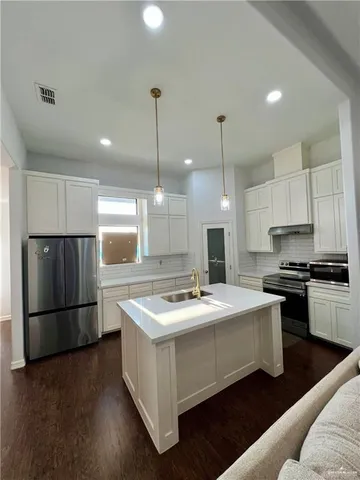 a kitchen with stainless steel appliances granite countertop a sink a stove a refrigerator and a oven