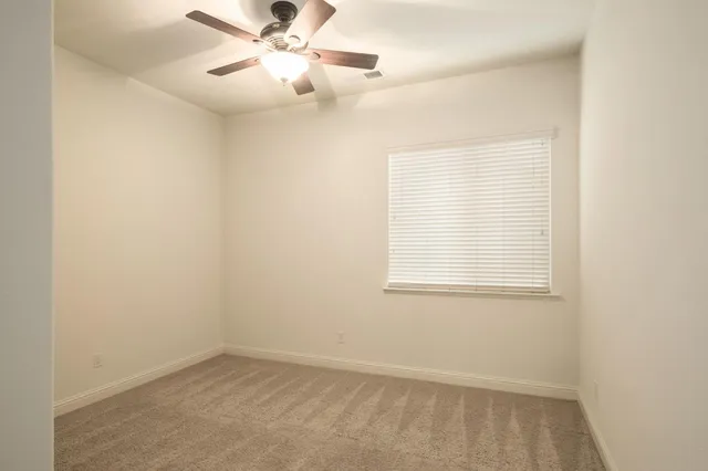 an empty room with a window and a fan