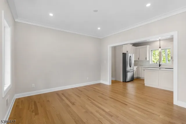 a view of an empty room with window and wooden floor