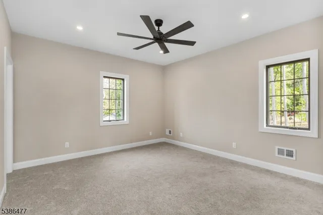 an empty room with ceiling fan and windows