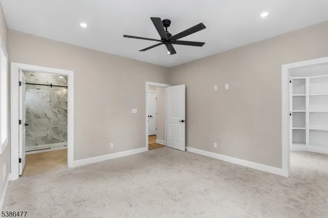 a view of a livingroom with a ceiling fan & windows