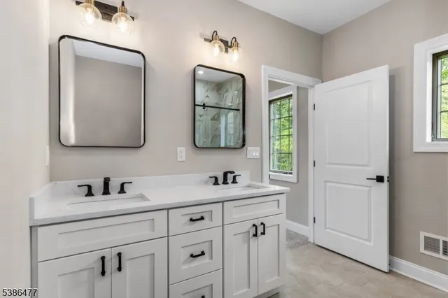 a bathroom with double vanity sink two mirror and a window
