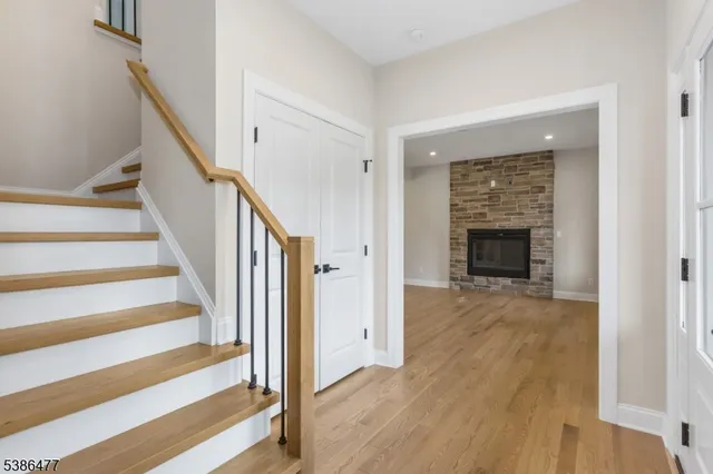 a view of an empty room with wooden floor fireplace and a window