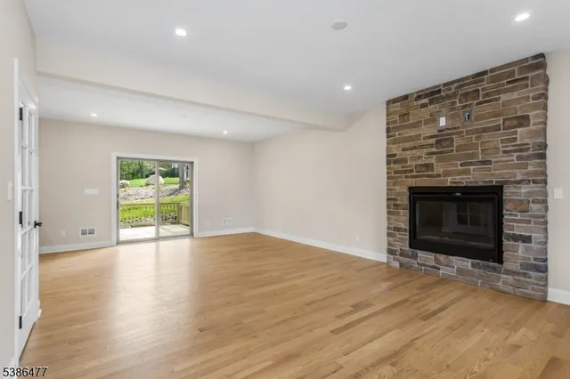 an empty room with wooden floor fireplace and window