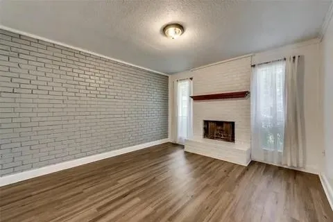 a view of an empty room with wooden floor fireplace and a window