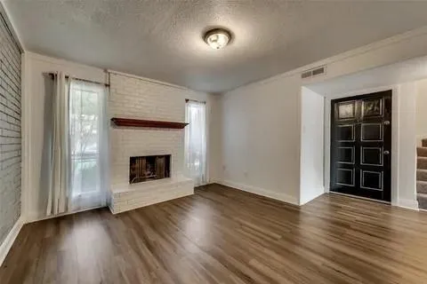 an empty room with wooden floor fireplace and windows