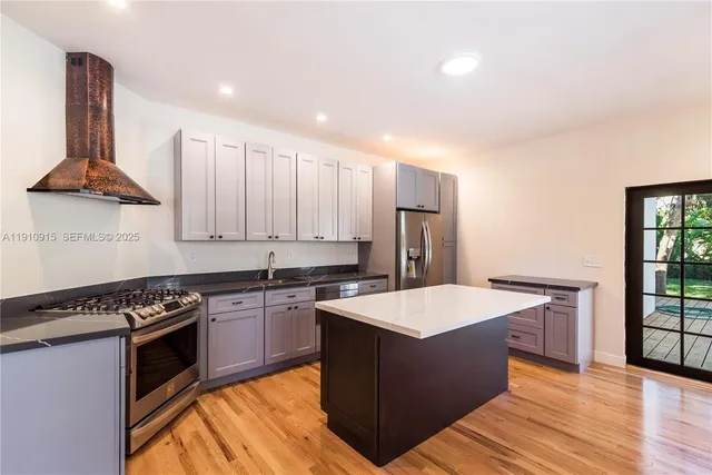 a kitchen with stainless steel appliances granite countertop a stove a sink dishwasher and a refrigerator with wooden floor