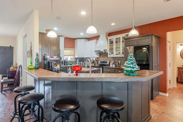 a kitchen with stainless steel appliances a dining table chairs sink and cabinets