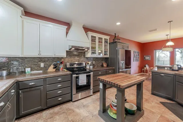 a kitchen with stainless steel appliances granite countertop a stove top oven a sink dishwasher and a refrigerator with wooden cabinets