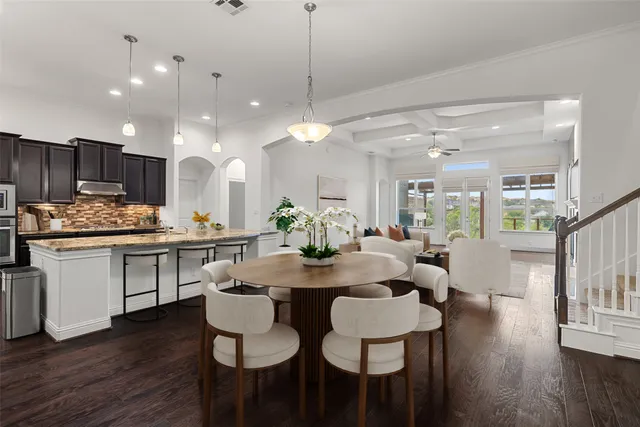a kitchen with a dining table chairs wooden floor appliances and cabinets