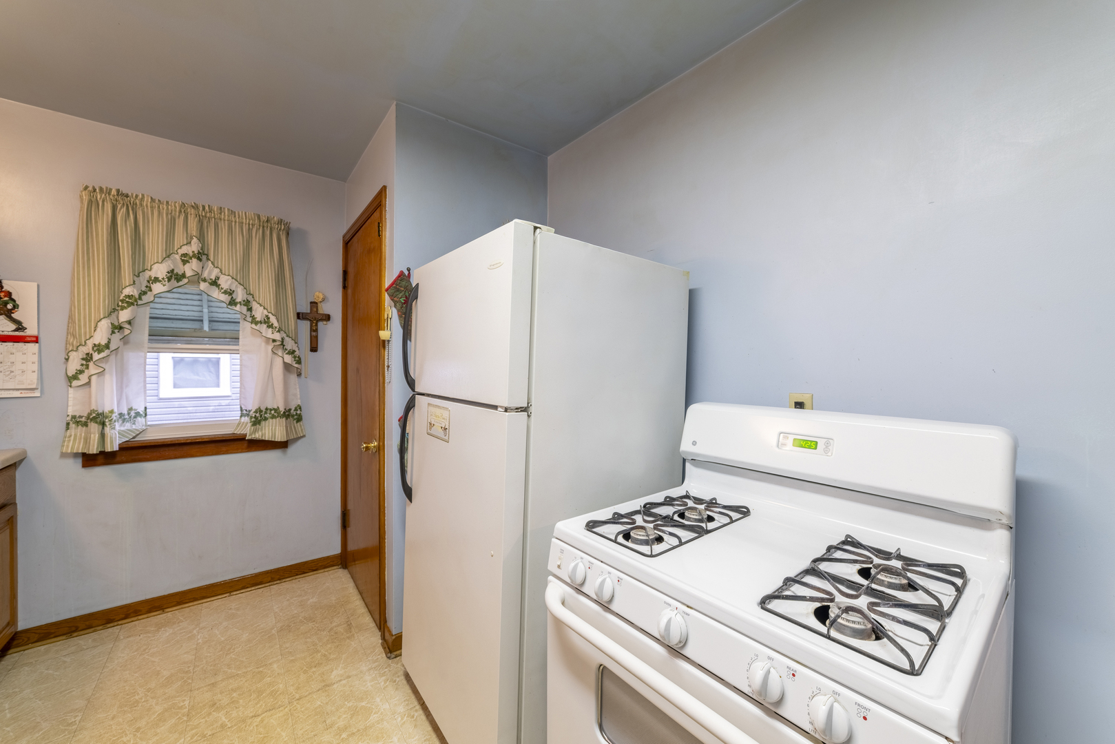 17949 Escanaba Avenue Lansing, IL 60438 - Photo 9 of 45 a kitchen with a refrigerator a stove a washer dryer and white cabinets