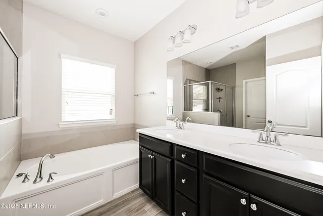 a bathroom with a tub a double vanity sink and a window