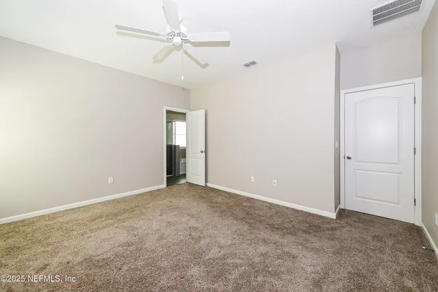 an empty room with ceiling fan and window