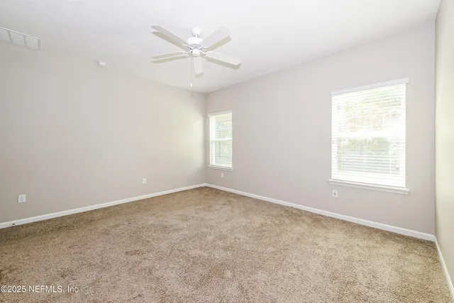 an empty room with a window and a fan
