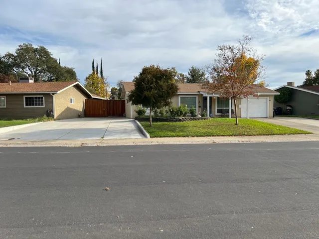front view of house with a yard and trees around