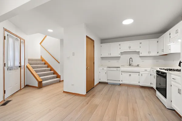 a kitchen with white cabinets stainless steel appliances and wooden floor