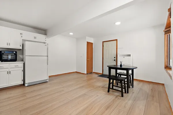 a kitchen with stainless steel appliances a refrigerator a stove a dining table and chairs with wooden floor