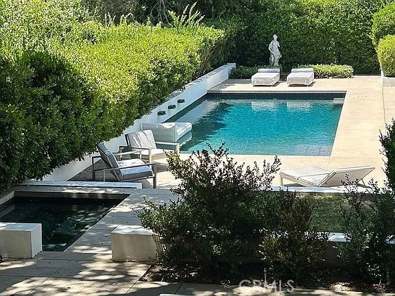 a view of swimming pool with lawn chairs and plants