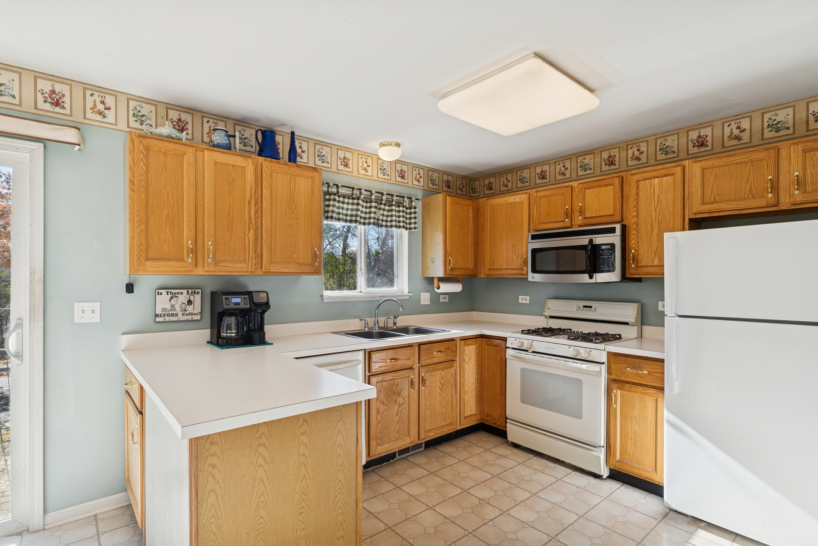 885 Charlton Road Lake Villa, IL 60046 - Photo 10 of 31 a kitchen with a sink a stove a refrigerator and white cabinets