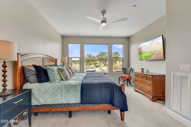 a bedroom with a bed and a flat tv screen on dresser