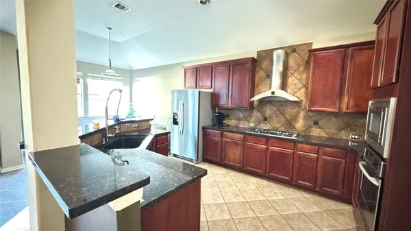 a kitchen with stainless steel appliances granite countertop a sink refrigerator and cabinets