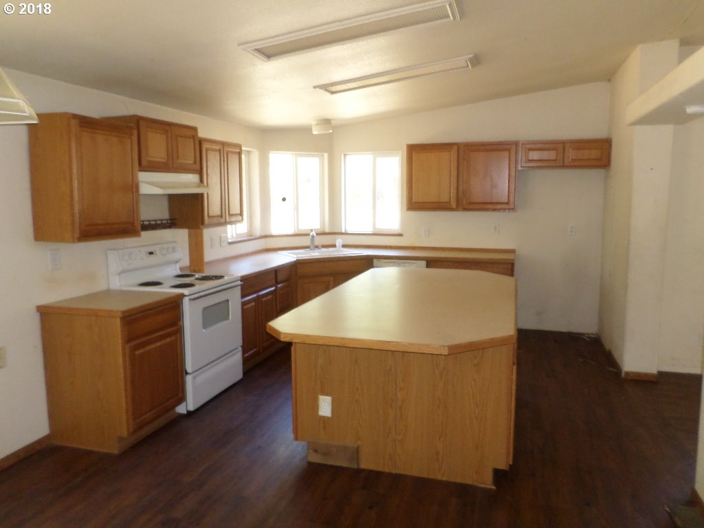 15063 South Hattan Road Oregon City, OR 97045 - Photo 9 of 25 a kitchen with wooden cabinets a sink a stove a microwave and wooden floors