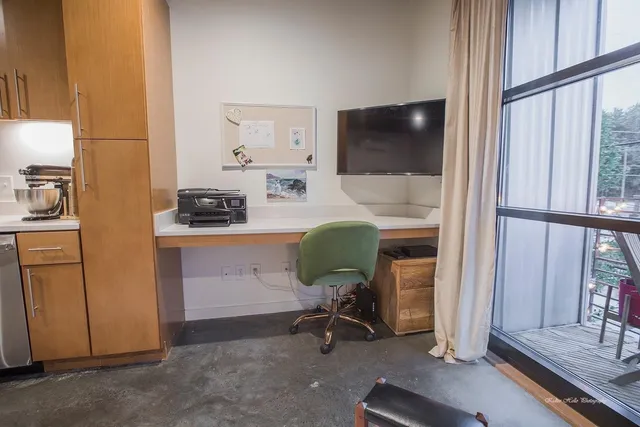 a view of a workspace with furniture and a window