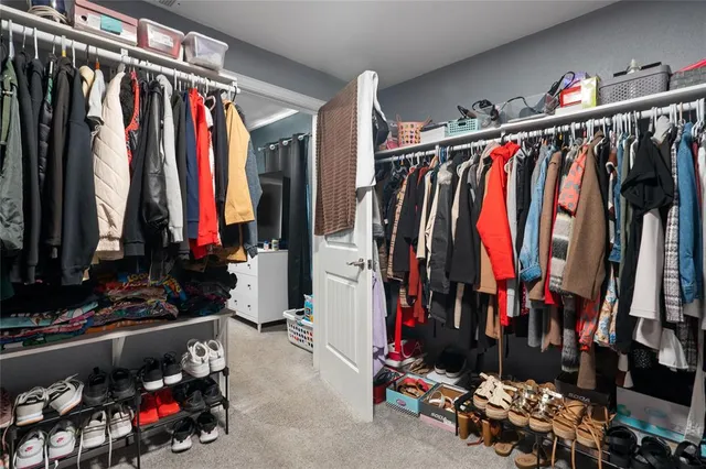 a view of walk in closet with clothes and shoes