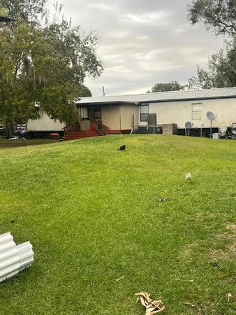 a front view of a house with a garden and lake