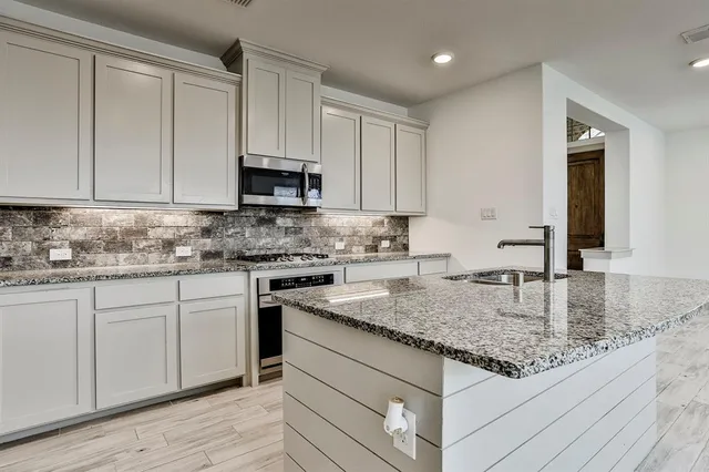 a kitchen with kitchen island granite countertop white cabinets a refrigerator and a sink