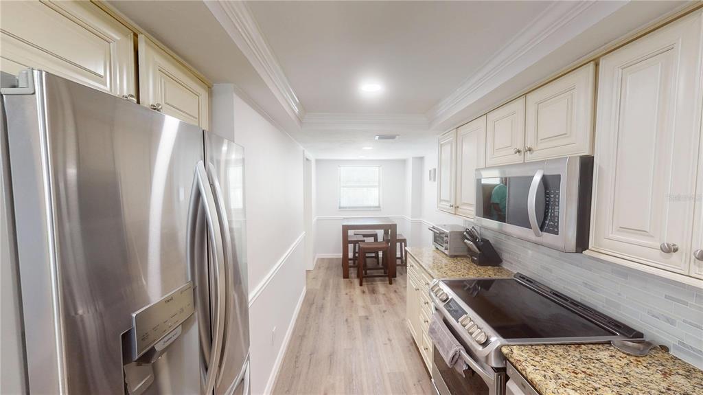 8735 Midnight Pass Road, Unit 206B Sarasota, FL 34242 - Photo 20 of 56 a kitchen with granite countertop a refrigerator a sink and wooden cabinets