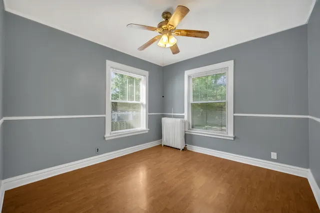 an empty room with windows and a ceiling fan