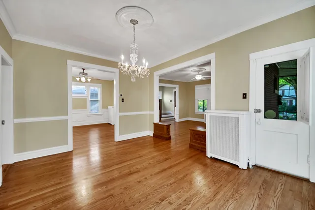 a view of a hallway with wooden floor and chandelier