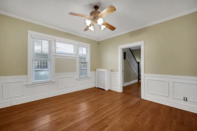 a view of empty room with wooden floor and fan