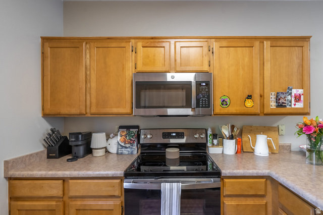 700 North Main Street, Unit F3 Washington, UT 84780 - Photo 9 of 34 Kitchen featuring wood-finish cabinetry, light-toned countertops, and a built-in stainless steel microwave