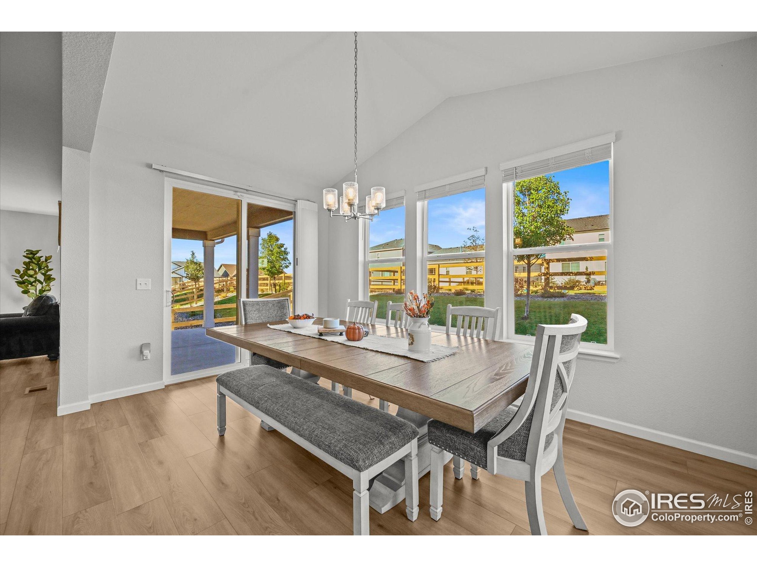 950 Rustling Street Windsor, CO 80550 - Photo 9 of 49 a dining room with wooden floor a chandelier a wooden table and chairs