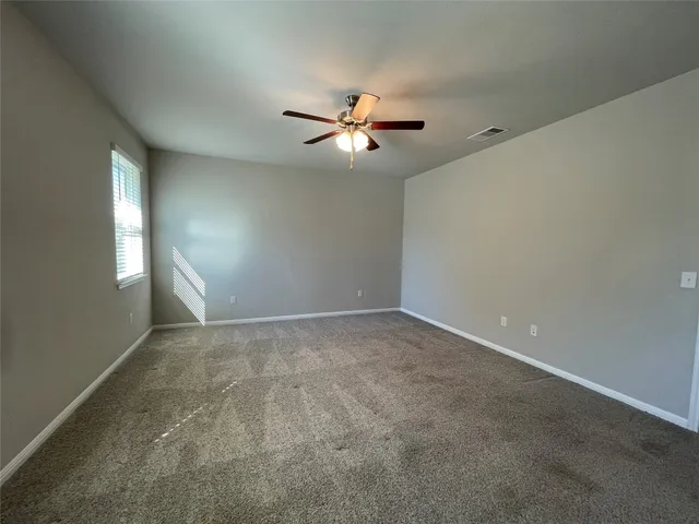 an empty room with windows and fan