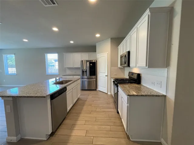 a large kitchen with a center island and stainless steel appliances