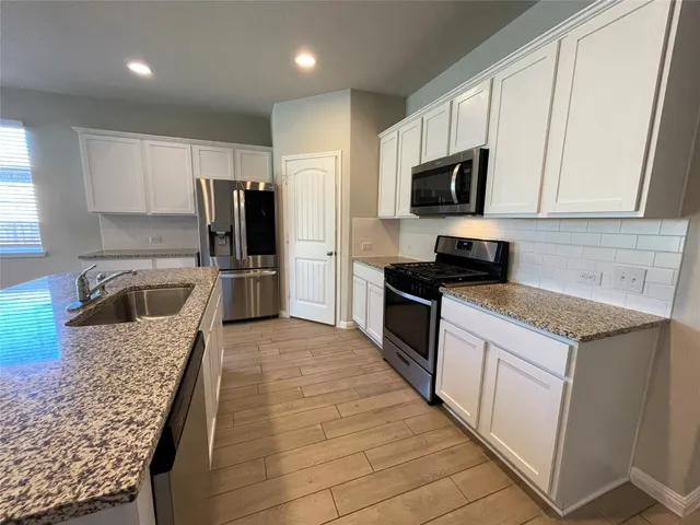 a kitchen with stainless steel appliances granite countertop a refrigerator stove microwave and sink