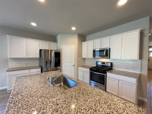 a kitchen with stainless steel appliances granite countertop a refrigerator sink and stove