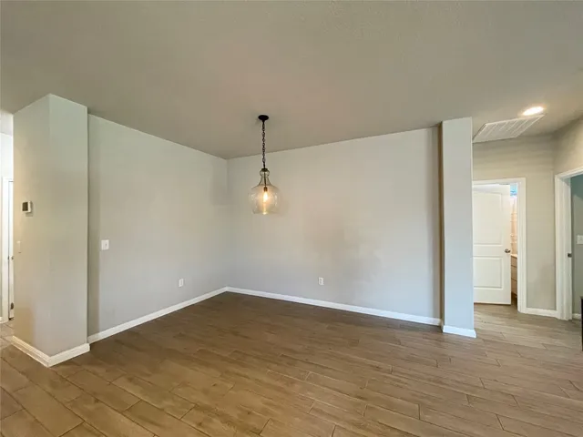 a view of an empty room with wooden floor and closet