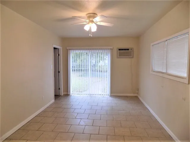 an empty room with a chandelier fan and windows