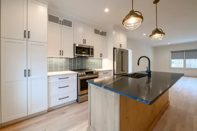 a kitchen with kitchen island granite countertop a sink and refrigerator