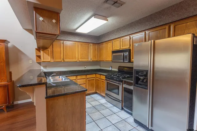 a kitchen with granite countertop stainless steel appliances a refrigerator stove top oven and sink