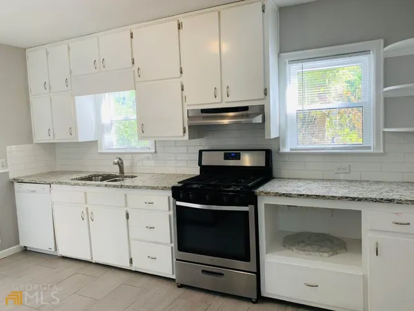 a kitchen with granite countertop white cabinets and appliances