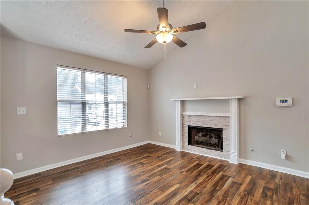 5918 Crescent Ridge Court Lithonia, GA 30058 - Photo 3 of 25 an empty room with windows a fireplace a ceiling fan and wooden floor