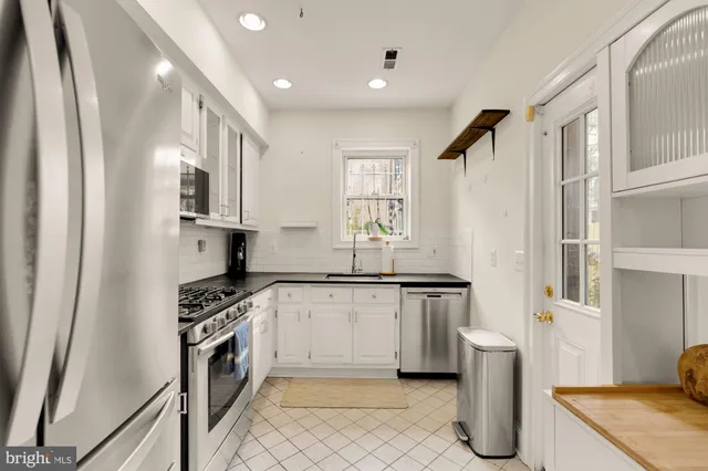 a kitchen with stainless steel appliances granite countertop white cabinets and a stove a oven with white countertops