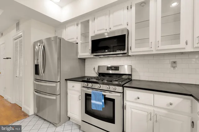 a kitchen with stainless steel appliances granite countertop white cabinets a window and a sink